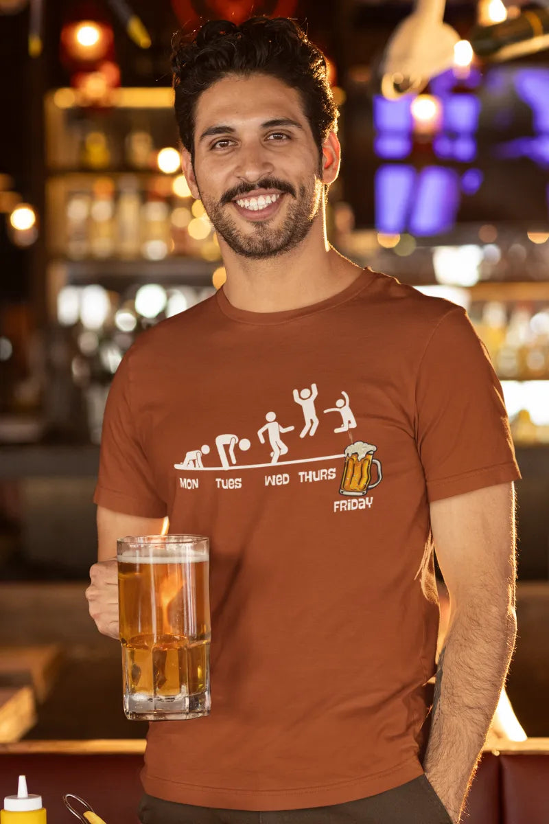 A man wearing a Rust brown cotton t-shirt with fun weekday-to-Friday evolution beer mug graphic worn by smiling man holding beer.