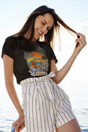 Woman wearing a black t-shirt with a colorful 'Beach Vibes' sunset and palm tree graphic