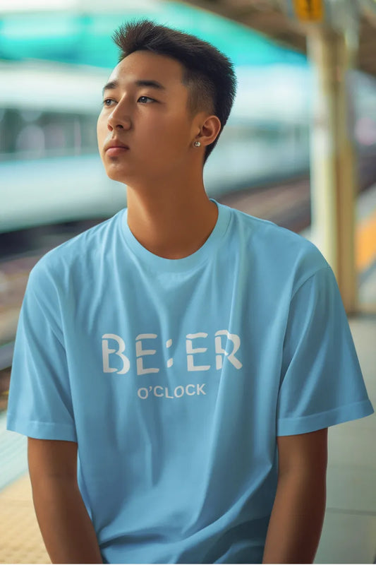 A man wearing a Sky blue T-shirt with bold white 'Beer O’Clock' quote printed on the chest