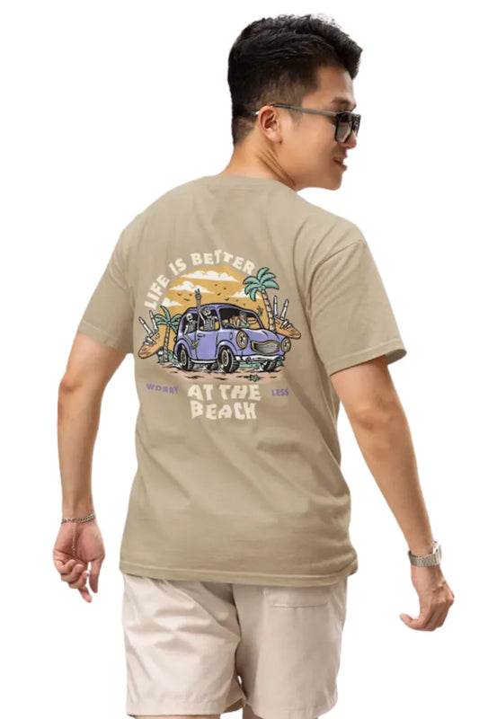 Man wearing a beige brown Double Impact T-shirt with beach skeleton and travel car design.