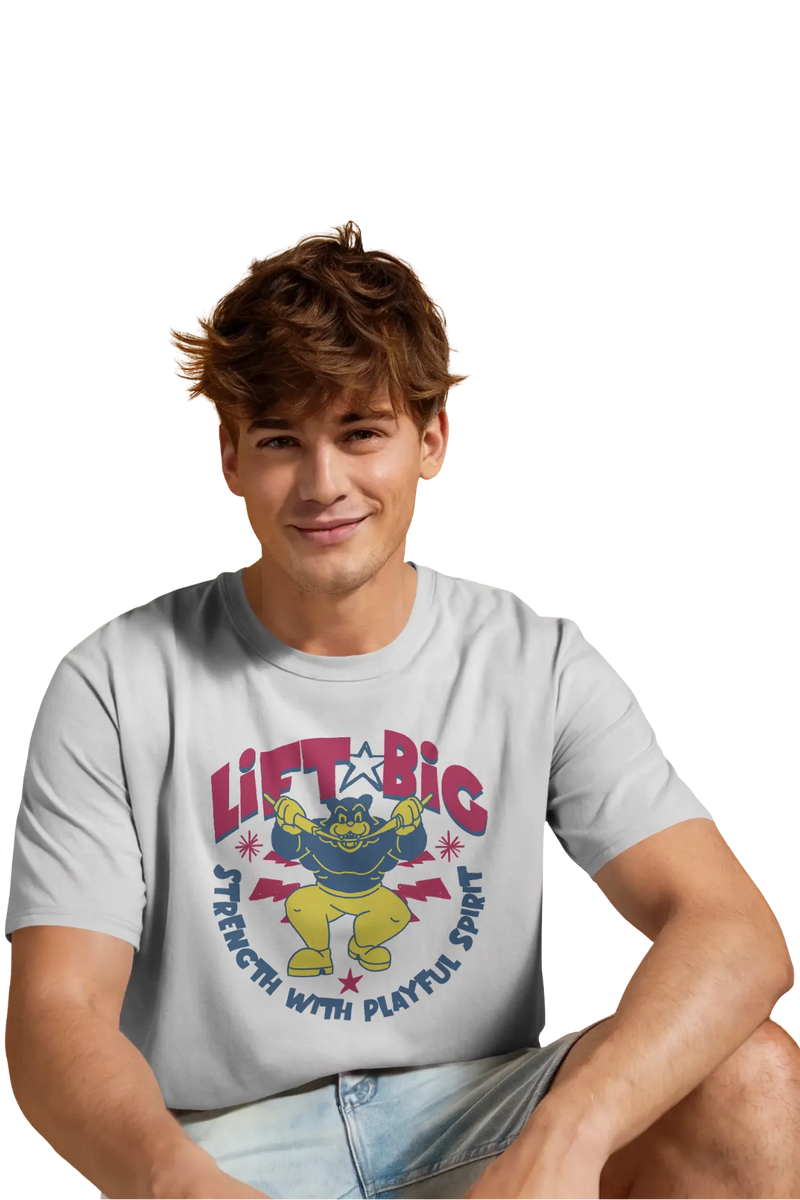 Man wearing an off-white cotton t-shirt with a cartoon graphic of a muscular character and the quote “Lift Big – Strength with Playful Spirit” printed on front.