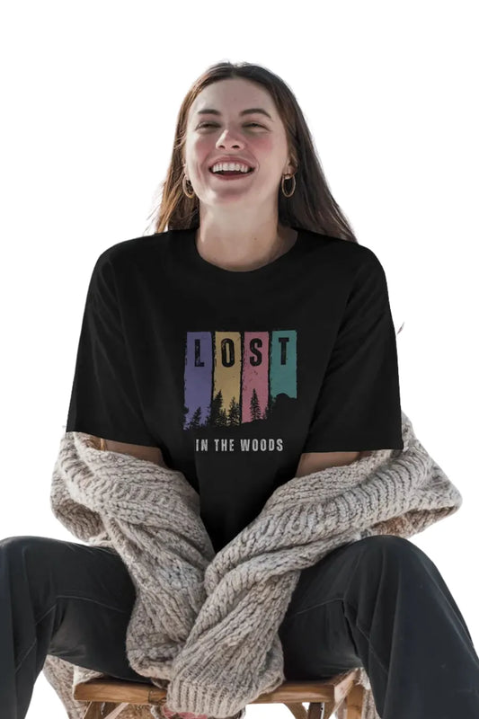 Woman smiling in black oversize t-shirt with colorful forest and 'Lost in the Woods' print
