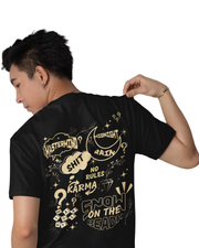 Man wearing a black cotton t-shirt with quirky graphic quotes like “Midnight Rain,” “Karma,” and “Snow on the Beach” printed in cream on the back and front.