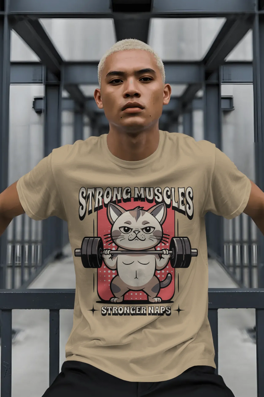 Man wearing beige brown cotton t-shirt with “Strong Muscles Stronger Naps” funny cat lifting weights graphic printed on front.