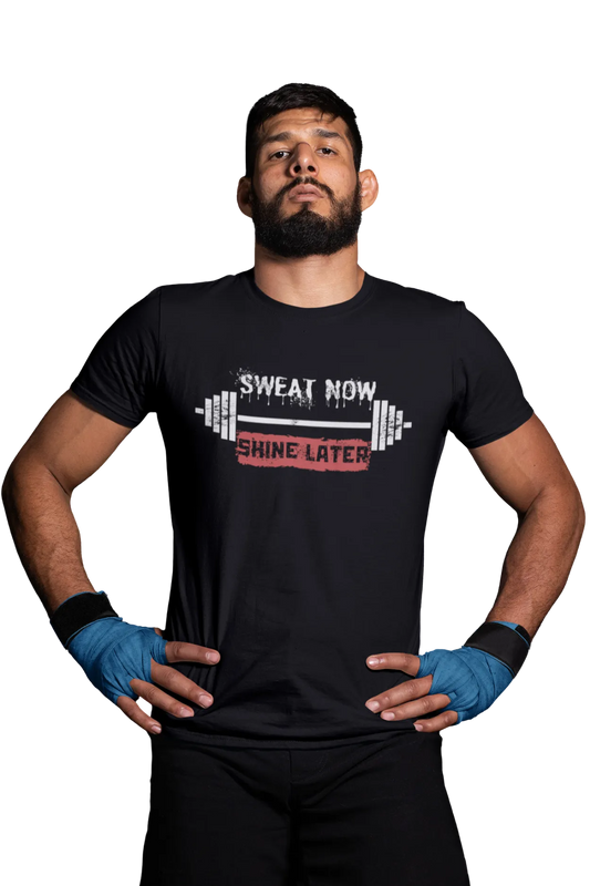 Man wearing a black cotton t-shirt with the quote “Sweat Now Shine Later” and barbell design printed on front.