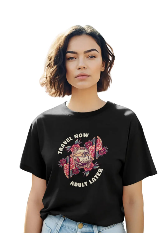 Woman wearing black oversized t-shirt with 'Travel Now Adult Later' design featuring floral and sunset graphics
